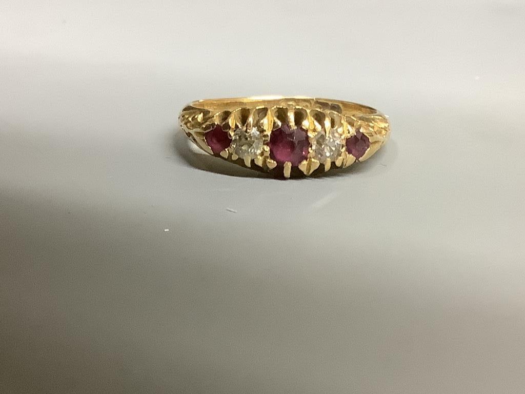 An Edwardian 18ct gold, three stone ruby and two stone diamond set half hoop ring